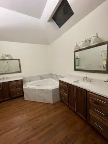 Primary bathroom remodel in Kansas City with a vaulted skylit ceiling, soaking tub, and dual vanities