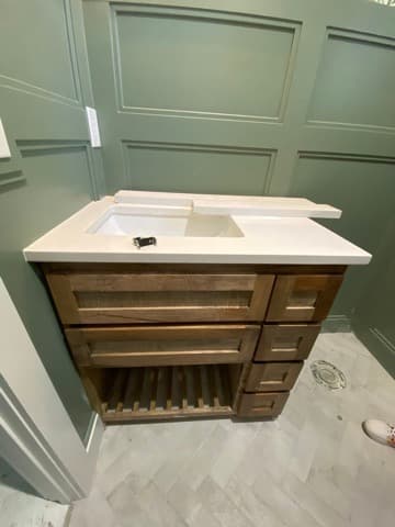 Bathroom vanity remodel with sage green wall paneling and a wood cabinet topped in white quartz