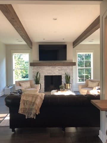 Living room with exposed wood ceiling beams and a stacked stone fireplace surround