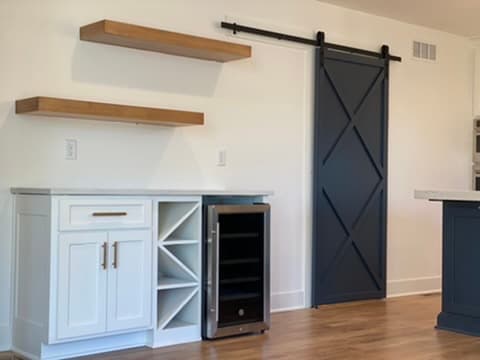 Floating wood shelves and a black sliding barn door in a custom kitchen nook