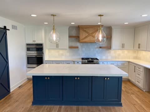 Kitchen remodel with a navy blue island, white cabinetry, and a custom wood vent hood