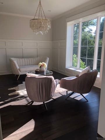 Sitting room with paneled wainscoting, a crystal chandelier, and a picture window
