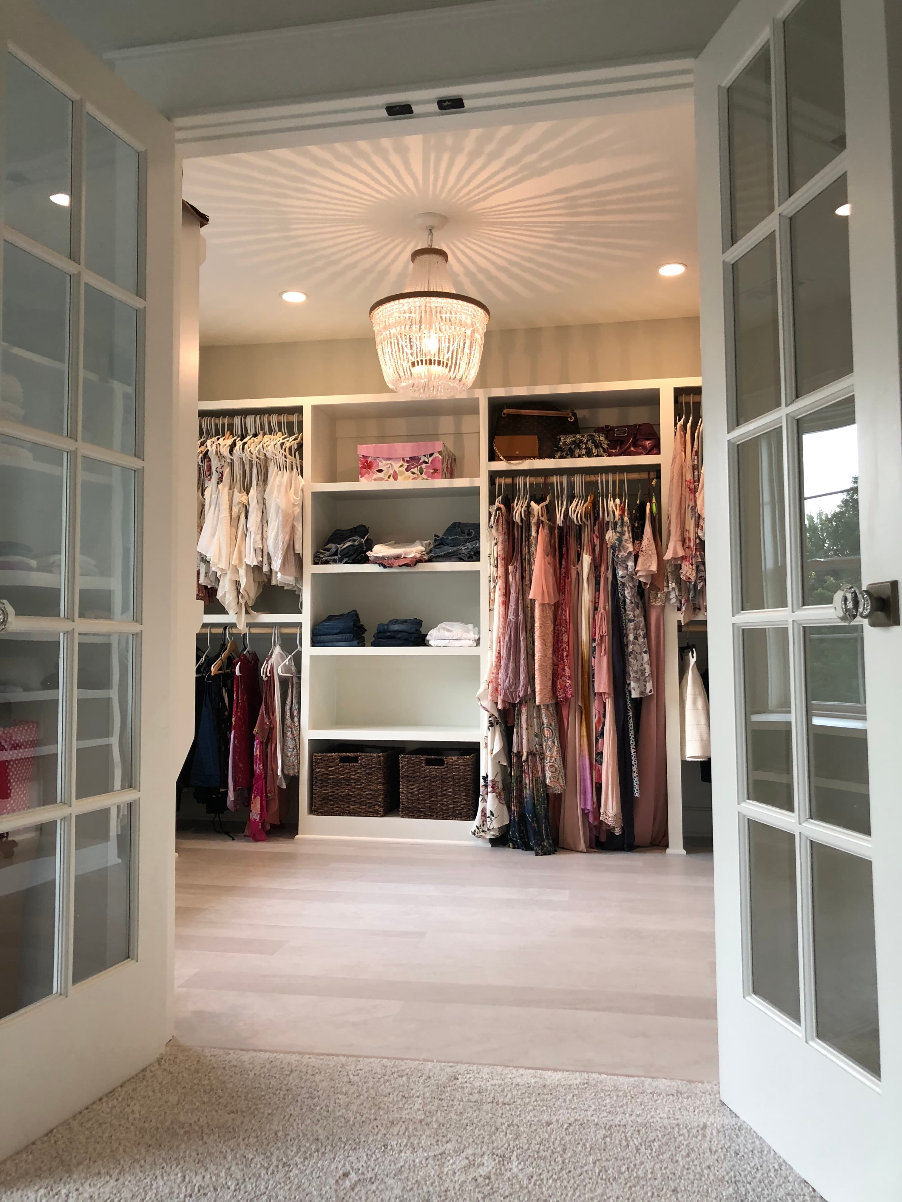 Walk-in closet interior with built-in shelving, hanging rods, and a sunburst ceiling light