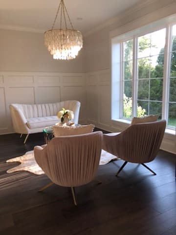 Sitting room with white panel wainscoting walls, a crystal chandelier, and a picture window